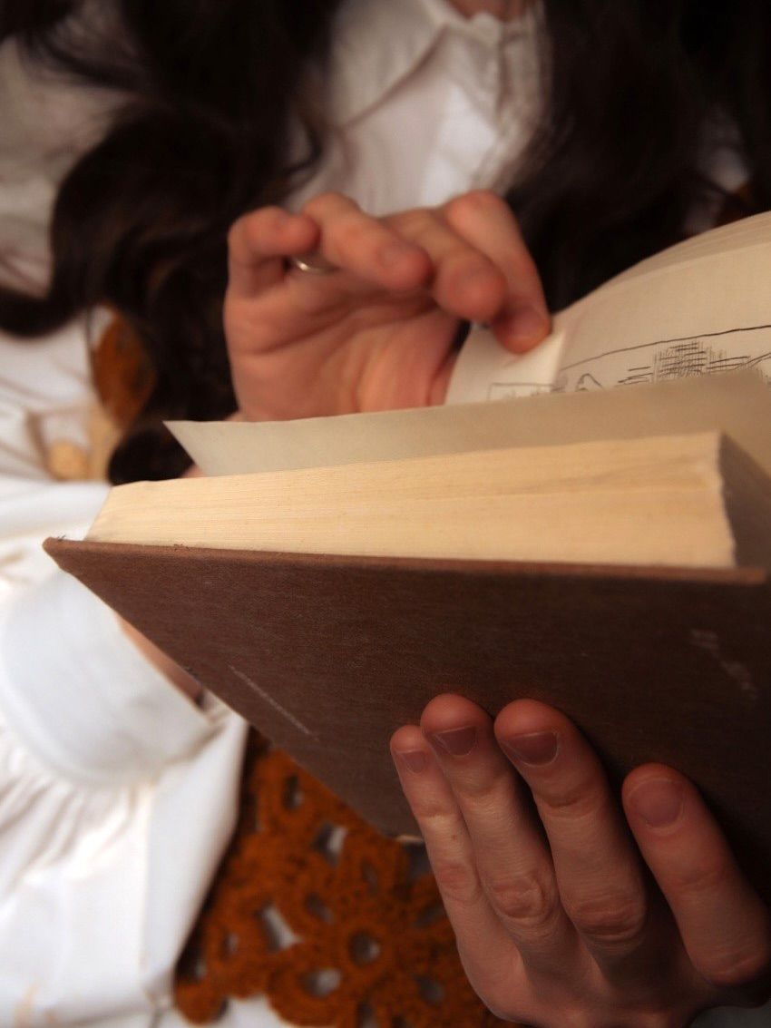 Крупный план рук, листающих старую книгу, тёплый свет
